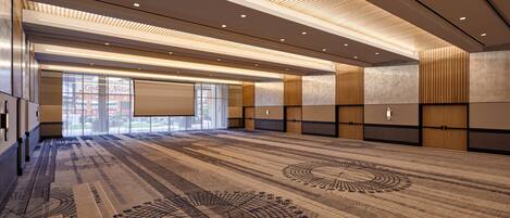 A spacious conference room with a patterned carpet, recessed lighting, and a large projection screen.