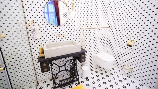 Un bagno con un water bianco, un lavabo nero con accessori dorati e uno specchio sopra il lavabo.