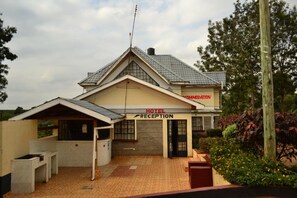 A hotel reception with a tiled roof, a signboard, and a small outdoor seating area. - Scenic View Hotel & Resort (Nairobi)