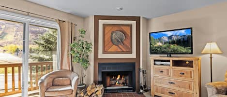 A living room with a fireplace, television, and a view of the outdoors.