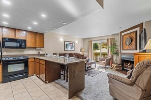 A modern kitchen with wooden cabinets, a built-in microwave, and a large island with bar stools. - Walk to Town Lift| Mountain View Balcony | Hot Tub| Managed by Park City Lodging (Park City)
