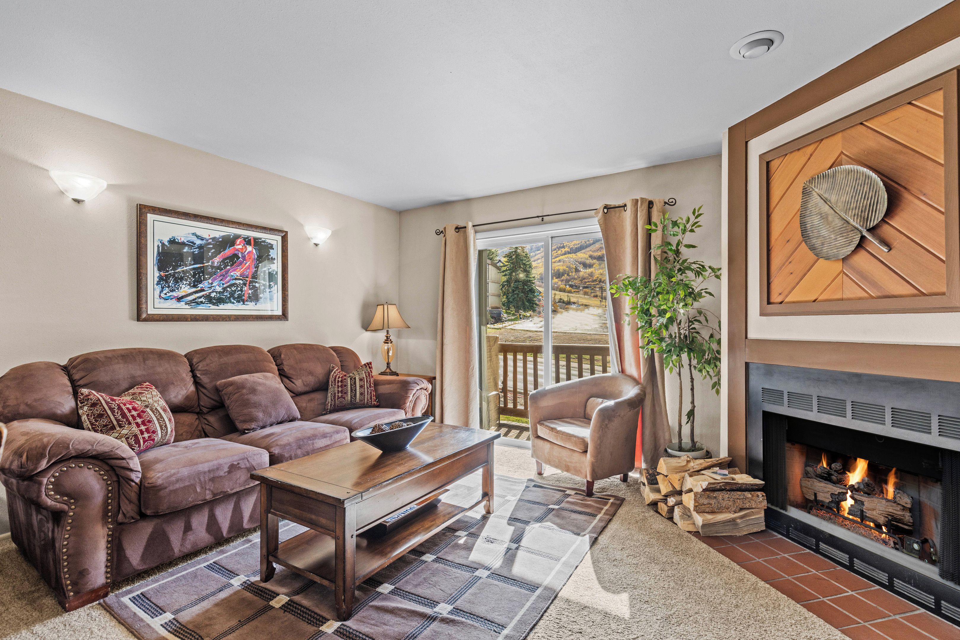Living room with fireplace, comfortable seating, balcony access and natural light.