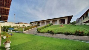 A hotel with a well-maintained lawn, a staircase leading to the building, and a clear sky.