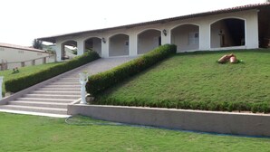A building with a sloped roof, a staircase leading to an entrance, and a well-maintained lawn.