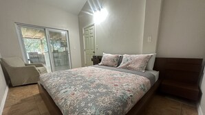 Une chambre avec un lit, une chaise, une porte et une vue sur l’extérieur, visible à travers une porte vitrée.