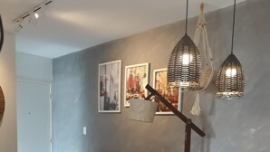 A modern living room with a sofa, dining table, and hanging pendant lights.