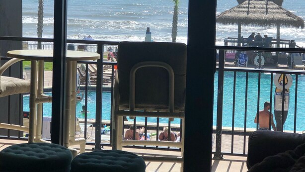 A room with a view of the ocean, a pool, and outdoor seating. - LONG TERM RENTAL ONLY- Oceanfront 1bed/1 bath condo (Daytona Beach Shores)