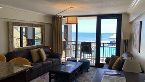A hotel room with a balcony, a sofa, a coffee table, a desk, and a chair. - LONG TERM RENTAL ONLY- Oceanfront 1bed/1 bath condo (Daytona Beach Shores)