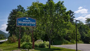 A sign for Mendon Mountain View Lodge with a road and greenery in the background. - Mendon Mountainview Lodge (Killington)