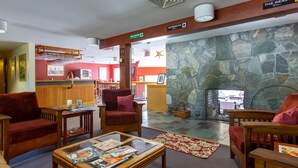 A lobby with wooden furniture, a stone fireplace, and a sign for "The Beast" restaurant. - Mendon Mountainview Lodge (Killington)
