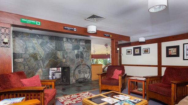 A lobby with wooden furniture, a stone wall, and a fireplace. - Mendon Mountainview Lodge (Killington)