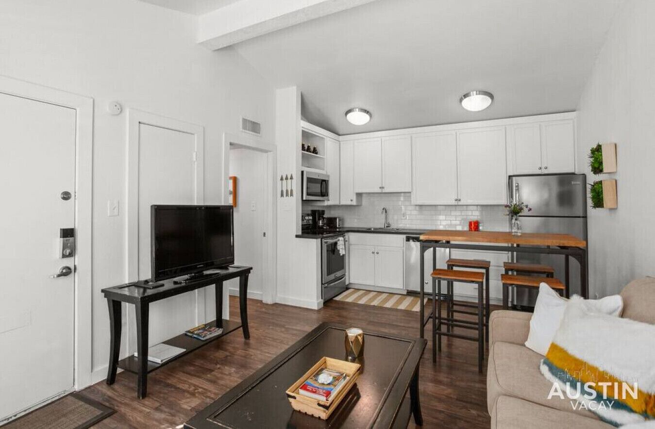 A compact living space with a kitchenette, a dining area, and a seating area with a sofa and coffee table.