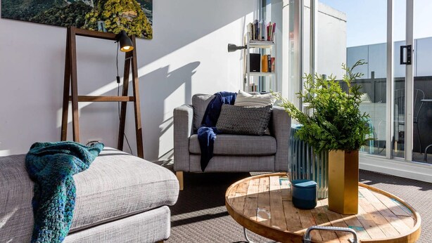 A modern living room with a grey sofa, a wooden coffee table, and a bookshelf. - Mika, 2bdr Fitzroy pad With Secure Parking (Fitzroy)