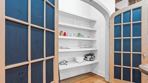 A kitchen with white shelves, a stove, and a wooden floor. - A REAL Fixer Upper - Giraffe House (Waco)