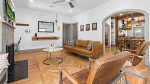 A spacious living room with a brown leather sofa, a round coffee table, and a ceiling fan. - A REAL Fixer Upper - Giraffe House (Waco)