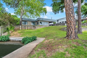 A modern house with a stone exterior, large windows, and a grassy yard. - Wake Zone-Lakefront w/ 1 Boat Lift & Dog Friendly (Kingsland)