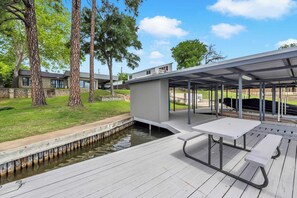 A covered outdoor area with a picnic table and benches, a small pond, and trees. - Wake Zone-Lakefront w/ 1 Boat Lift & Dog Friendly (Kingsland)