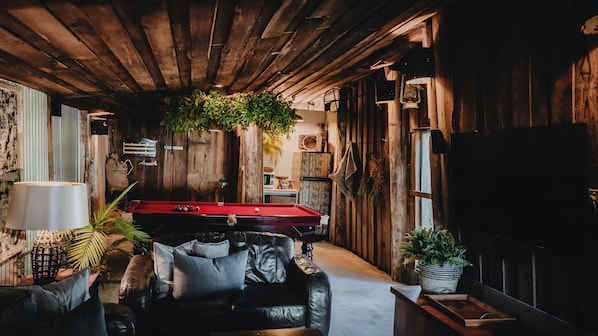 Un espace intérieur chaleureux et accueillant, avec une table de billard, un canapé en cuir et des murs en bois.