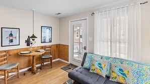 Una sala de estar acogedora con una mesa de comedor de madera, un sofá gris y almohadones decorativos.