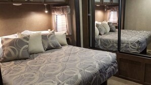 A bedroom with two beds, each with patterned bedding and pillows, and a large mirror reflecting the room. - Family Time at Hills Hocking @ Pine Creek Villas: Creek Front (Rockbridge)