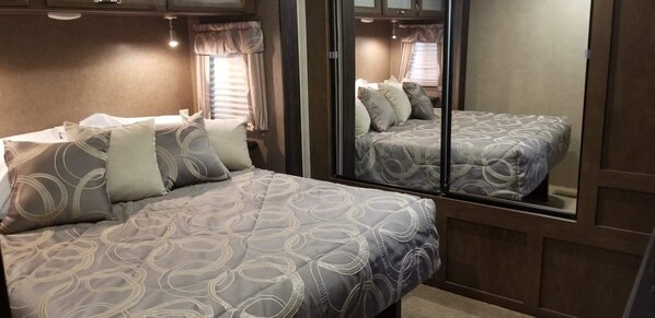 A bedroom with two beds, each with patterned bedding and pillows, and a large mirror reflecting the room. - Family Time at Hills Hocking @ Pine Creek Villas: Creek Front (Rockbridge)