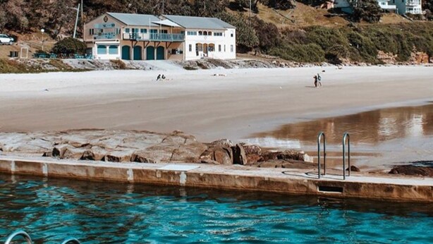 Ein Strandgrundstück mit Pool, Strand und einem Gebäude mit mehreren Fenstern und Balkonen.