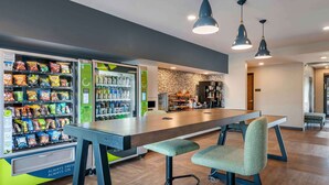 A modern kitchen area with a long counter, bar stools, and vending machines offering snacks and drinks. - Extended Stay America Premier Suites Tampa Gibsonton Rivervi (Gibsonton)