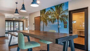 A conference room with a long table, two chairs, and a mural of palm trees on the wall. - Extended Stay America Premier Suites Tampa Gibsonton Rivervi (Gibsonton)
