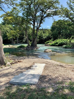 A riverside area with a concrete platform, surrounded by trees and greenery.