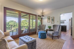 A spacious living area with a large sliding glass door leading to a balcony, a grey armchair, a blue ottoman, and a small table with a plant. - Cottonseed Falls I River Access, Family fun (Martindale)