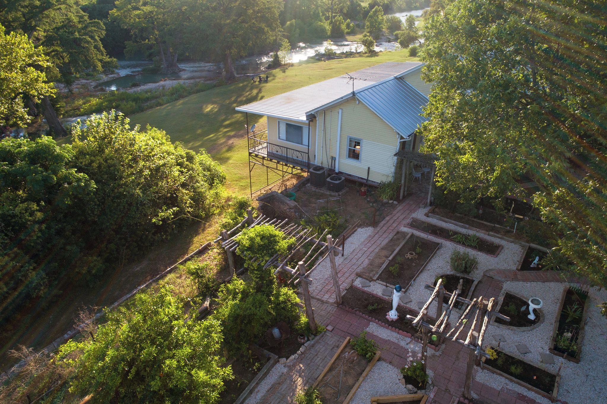 A house with a blue roof, a porch, and a garden with raised beds.