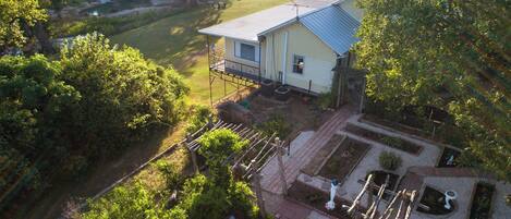 A house with a blue roof, a porch, and a garden with raised beds.