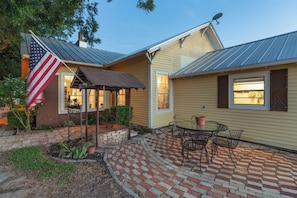 Een huis met een terras van bakstenen, een overdekte zithoek en een Amerikaanse vlag.