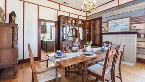 A traditional dining room with a wooden table and chairs, a chandelier, and a fireplace.