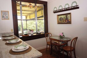 A dining area with a round glass table, wooden chairs, and a window with a view of greenery. - Cottonseed Falls I River Access, Family fun (Martindale)
