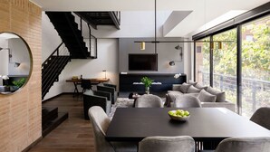 Un salon moderne comprenant un coin repas, un escalier et une cuisine équipée d’un téléviseur.