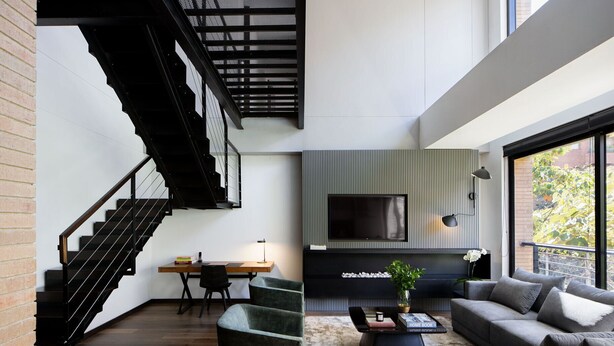 Un salon moderne avec un escalier, un téléviseur à écran plat et un coin salon confortable.