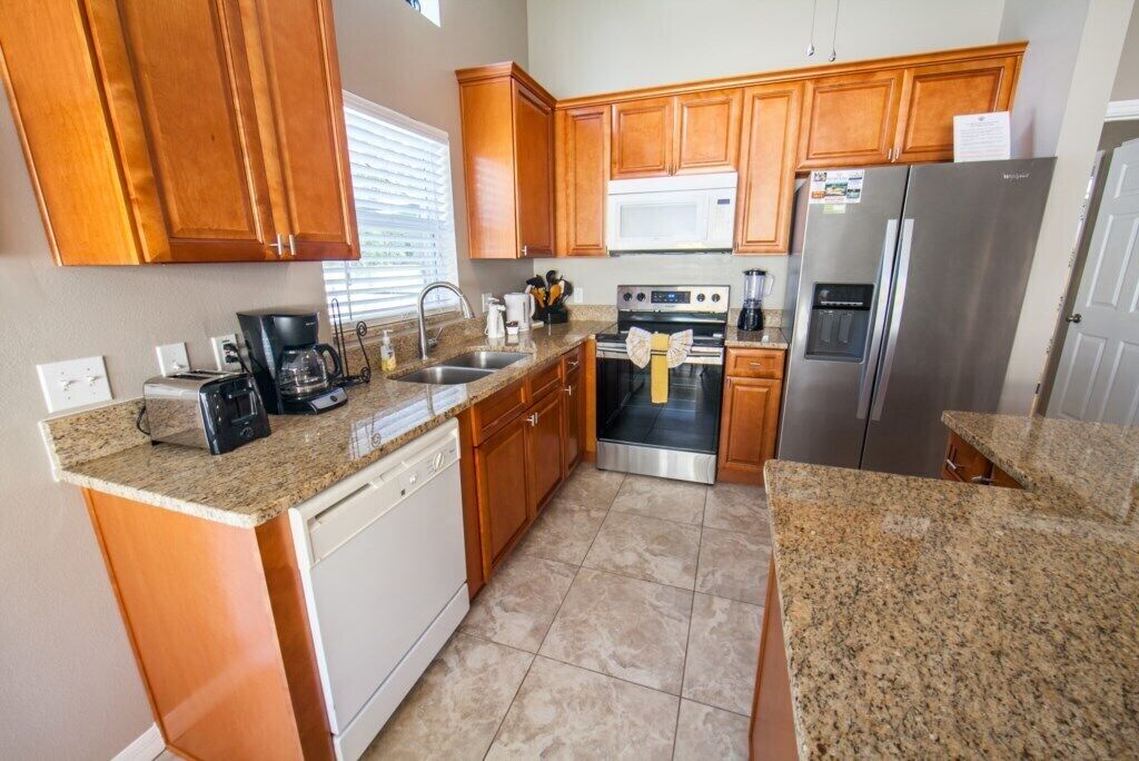 A kitchen with wooden cabinets, granite countertops, stainless steel appliances, and a dishwasher.