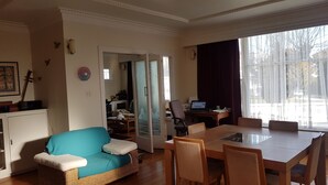 A living room with a sofa, dining table, chairs, and a laptop on a desk. - Character home, city close (Inner Kaiti)