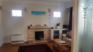 A living room with a fireplace, a sofa, a coffee table, and a window. - Character home, city close (Inner Kaiti)