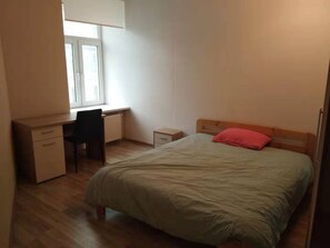 A bedroom with a bed, a desk, and a chair.