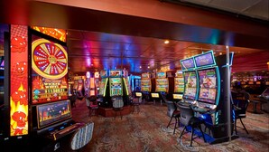 Een casino-interieur met gokkasten en een groot draaiend rad.
