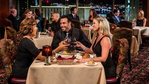 Een restaurant met gedekte tafels, een stadszicht en een groot raam.