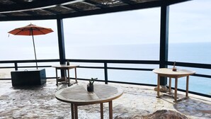 A terrace with round tables, a red umbrella, and a view of the sea. - Cabo Private 3bed,3bath Condo + Fober Optic WiFi, Spacious Condo at Quivira Golf (Cabo San Lucas)