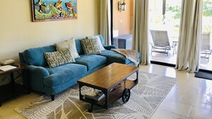 A living room with a blue sofa, a wooden coffee table, patterned cushions, a rug, and a painting of fish on the wall. - Cabo Private 3bed,3bath Condo + Fober Optic WiFi, Spacious Condo at Quivira Golf (Cabo San Lucas)