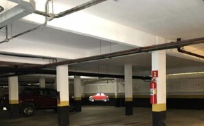 Een meerlaags parkeergarage met betonnen pilaren en een brandblusser.