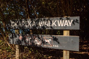 A sign for Okareka Walkway with symbols indicating no dogs, no bicycles, and no pigs allowed.