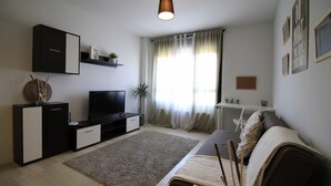 A modern living room with a flat-screen TV, a sofa, a coffee table, and a large window with curtains. - Avilés-Salinas V. U.T. 612-AS (salinas/castrillon)