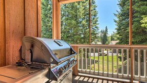 Ein Grill auf einem Balkon mit Blick auf eine grüne Landschaft und einen weißen Zaun.