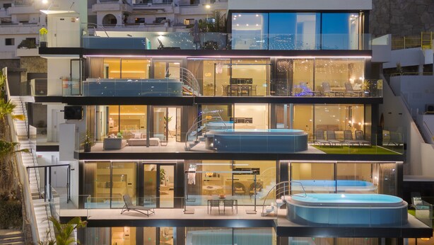 Un edificio moderno a più piani con piscina sul tetto, ringhiere in vetro e una scala.